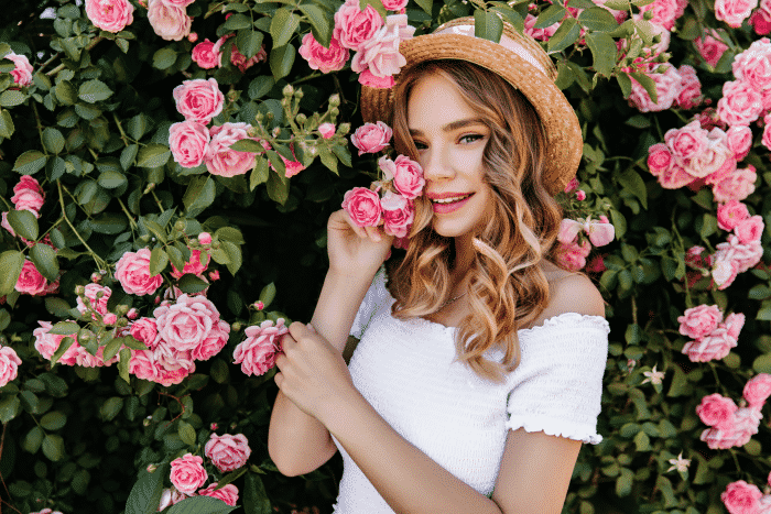 outdoor-portrait-happy-white-girl-posing-nature-photo-relaxed-lady-with-wavy-hair-standing-near-beautiful-rose-bush